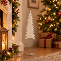 A small white wooden Christmas tree stand with a textured finish and a gold-colored metal stake, set on a wooden floor in a cozy, warmly lit holiday living room next to a decorated Christmas tree and fireplace.